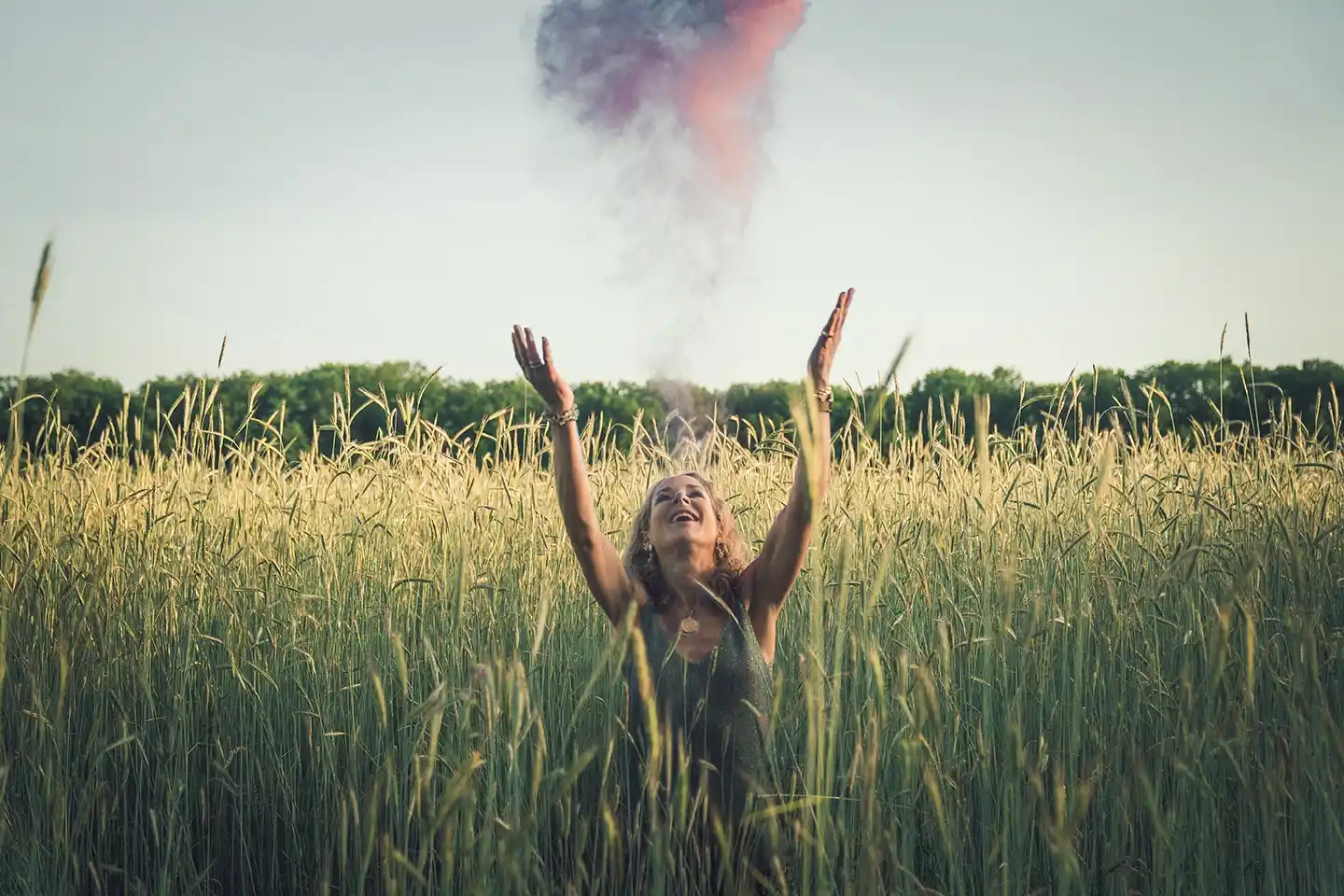 Therapeut Michelle Storimans glimlacht in een veld met kleurrijk poeder in de lucht