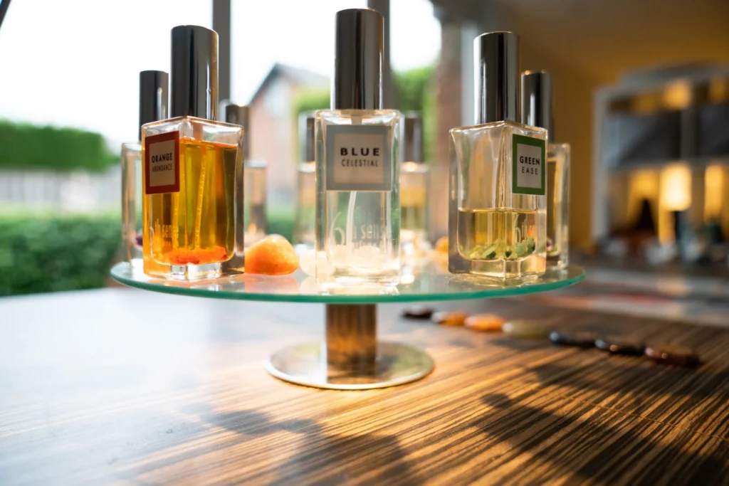 Een selectie aromatische sprayflacons, uitgestald op een glazen standaard in een rustige, goed verlichte therapieruimte